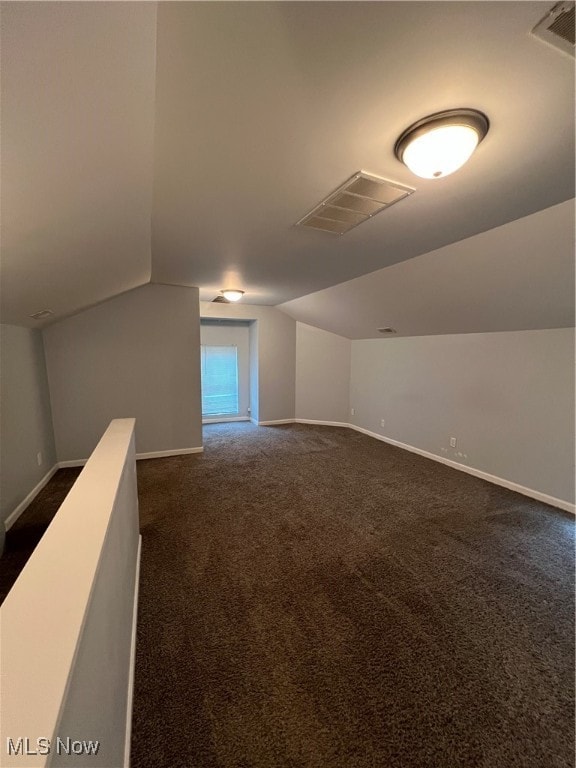 bonus room with lofted ceiling and dark colored carpet