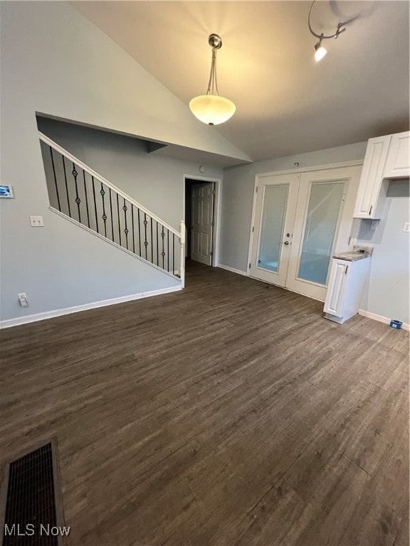 unfurnished living room featuring vaulted ceiling and dark wood-type flooring