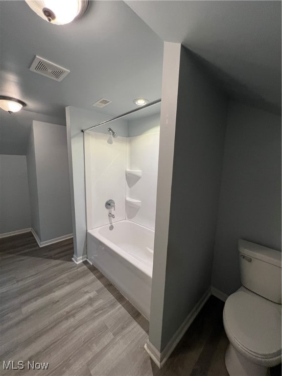 bathroom with wood-type flooring, bathtub / shower combination, and toilet