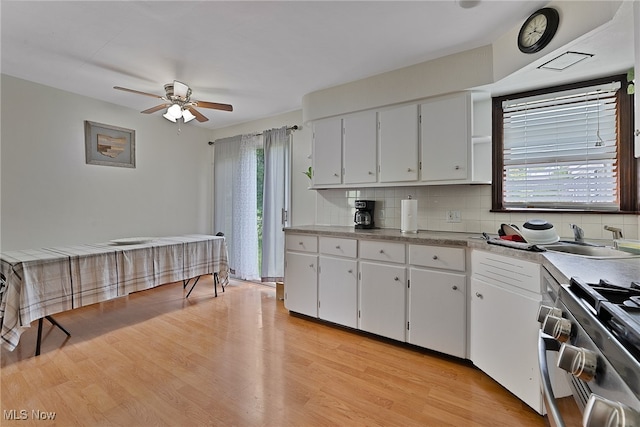 kitchen featuring white cabinets, light wood-type flooring, a healthy amount of sunlight, and stainless steel gas range