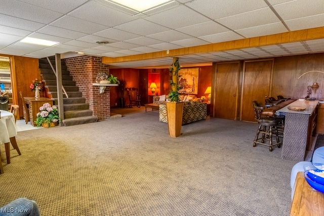 rec room featuring light carpet, wood walls, and a paneled ceiling