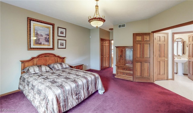 carpeted bedroom featuring connected bathroom and sink