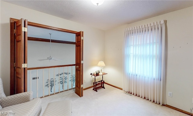 sitting room with a textured ceiling, light carpet, and ceiling fan