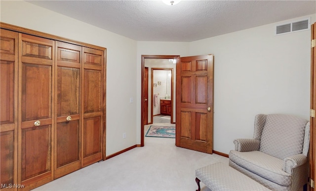 sitting room with a textured ceiling and light carpet