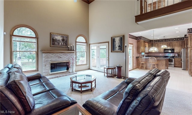 living room with a brick fireplace, a high ceiling, and a healthy amount of sunlight