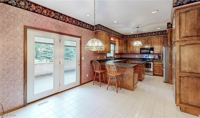 kitchen featuring a breakfast bar area, appliances with stainless steel finishes, hanging light fixtures, and kitchen peninsula