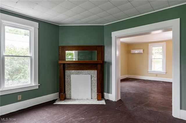 unfurnished living room featuring ornamental molding, dark hardwood / wood-style floors, a fireplace, and a wealth of natural light