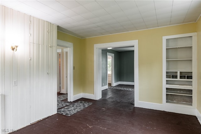 unfurnished room with dark wood-type flooring and built in shelves