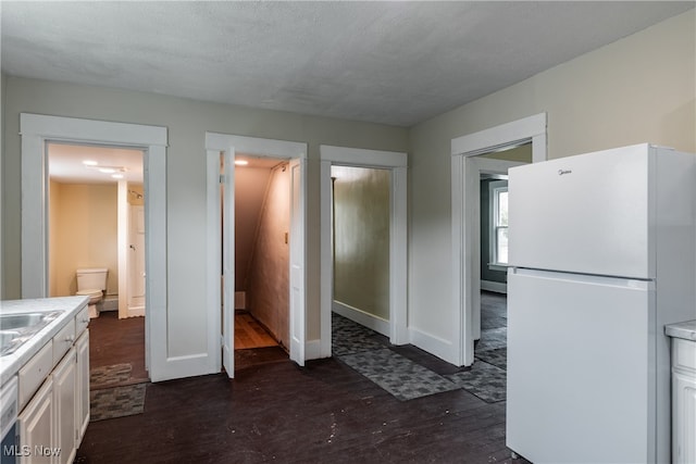 kitchen featuring a textured ceiling, white cabinetry, white fridge, and dark hardwood / wood-style floors