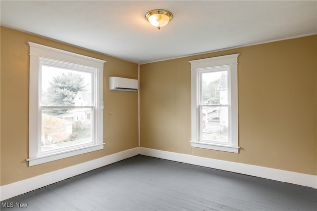 empty room featuring a healthy amount of sunlight, dark hardwood / wood-style flooring, and a wall mounted air conditioner