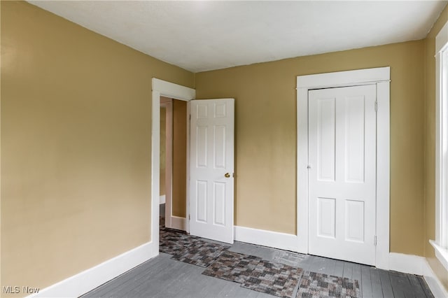 unfurnished bedroom featuring a closet and dark hardwood / wood-style floors