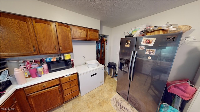 kitchen featuring fridge, stainless steel refrigerator with ice dispenser, and a textured ceiling