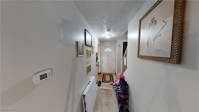 corridor featuring light carpet and a textured ceiling