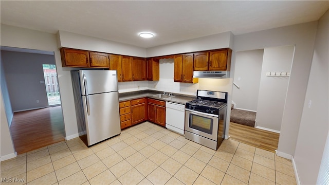 kitchen featuring stainless steel appliances, light wood-type flooring, sink, and tasteful backsplash