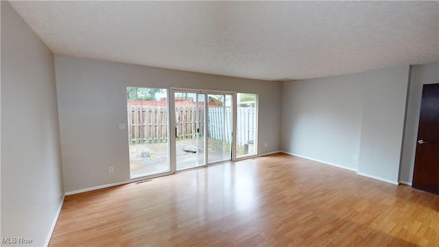 unfurnished room featuring a textured ceiling and light hardwood / wood-style flooring