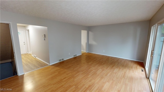 empty room featuring a textured ceiling and light hardwood / wood-style floors