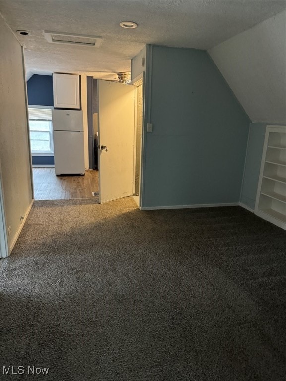 bonus room with lofted ceiling, a textured ceiling, hardwood / wood-style flooring, and built in features