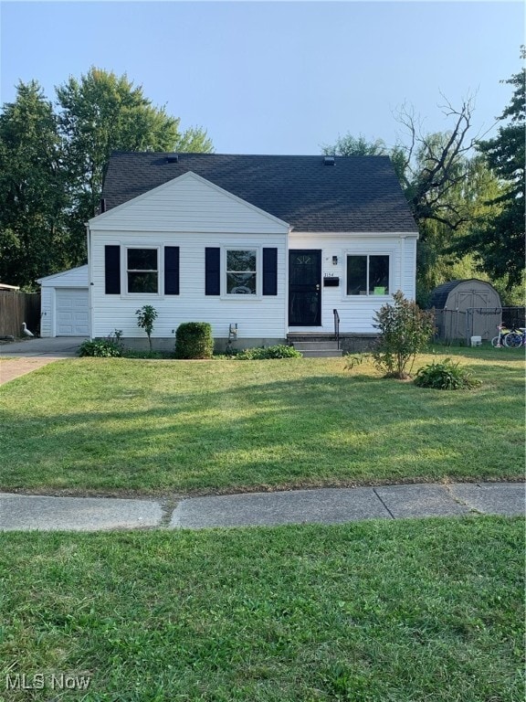 single story home featuring a storage shed, a garage, and a front yard