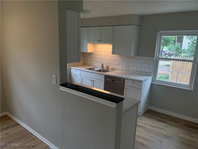 kitchen with light wood-type flooring, dishwasher, sink, and white cabinets