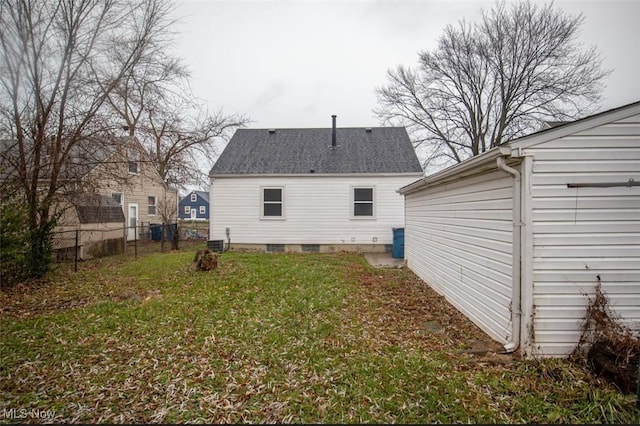 rear view of property with central air condition unit and a lawn