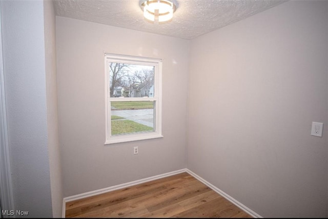 empty room with hardwood / wood-style floors and a textured ceiling