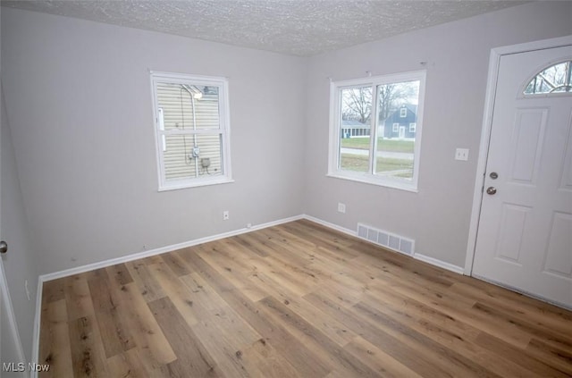 foyer entrance with a textured ceiling and light hardwood / wood-style floors