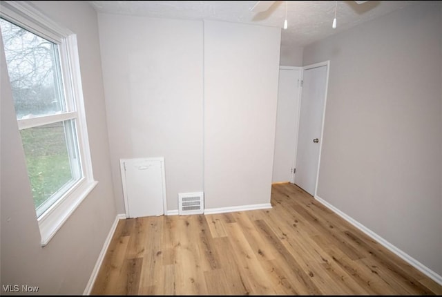 unfurnished bedroom with ceiling fan, multiple windows, and light wood-type flooring