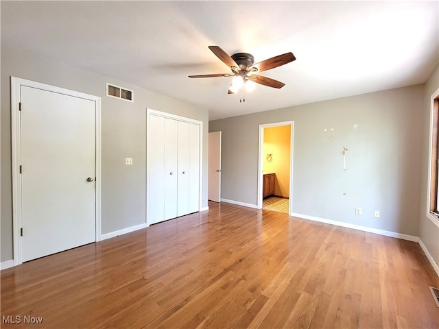 unfurnished bedroom with light wood-type flooring, ensuite bath, and ceiling fan