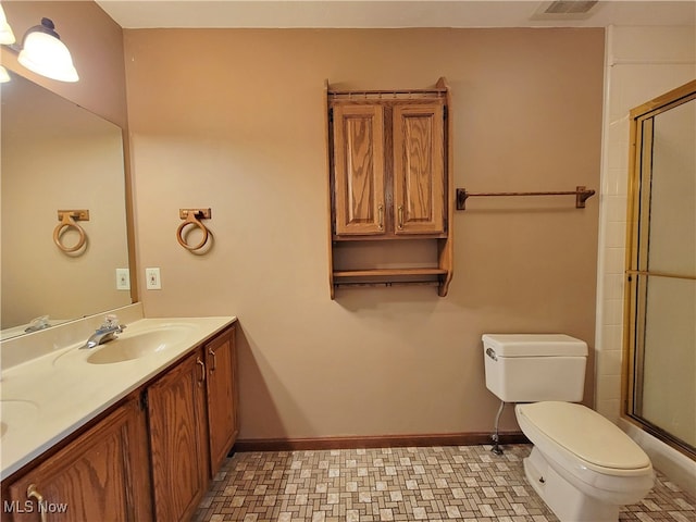 bathroom with vanity, a shower with shower door, and toilet