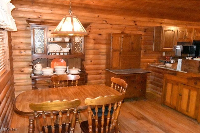 dining area with light hardwood / wood-style flooring, wood ceiling, and rustic walls