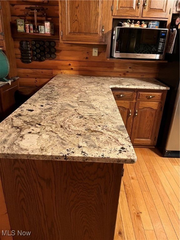 kitchen with light hardwood / wood-style floors, light stone countertops, and black refrigerator