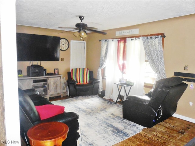 living room with wood-type flooring, ceiling fan, and a textured ceiling