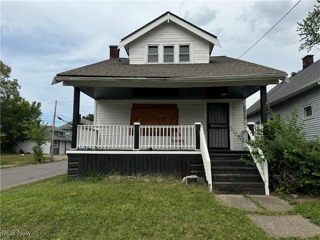 bungalow-style home with a front yard and covered porch