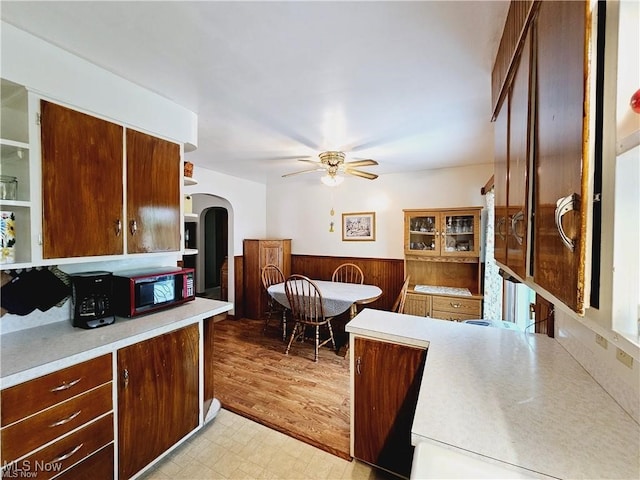 kitchen featuring ceiling fan, wooden walls, and light wood-type flooring