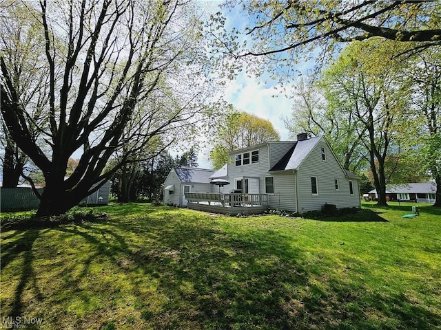 back of house with a wooden deck and a lawn