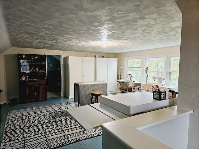 kitchen featuring a textured ceiling, white cabinetry, and hardwood / wood-style floors