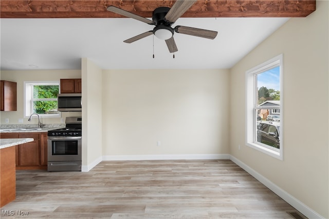 kitchen with light hardwood / wood-style flooring, stainless steel appliances, beam ceiling, and a wealth of natural light