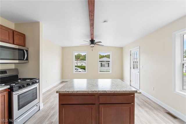 kitchen featuring vaulted ceiling with beams, light stone countertops, a kitchen island, appliances with stainless steel finishes, and light wood-type flooring