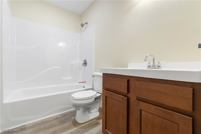 full bathroom featuring wood-type flooring, washtub / shower combination, vanity, and toilet