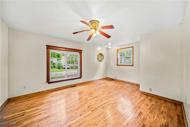 spare room with ceiling fan, plenty of natural light, and light hardwood / wood-style floors