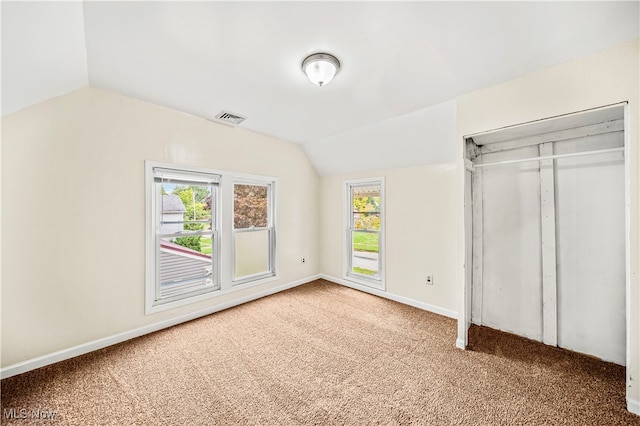 unfurnished bedroom with lofted ceiling, carpet, and multiple windows