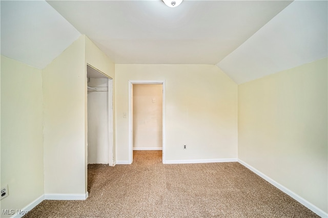 unfurnished bedroom with light colored carpet, a closet, and vaulted ceiling