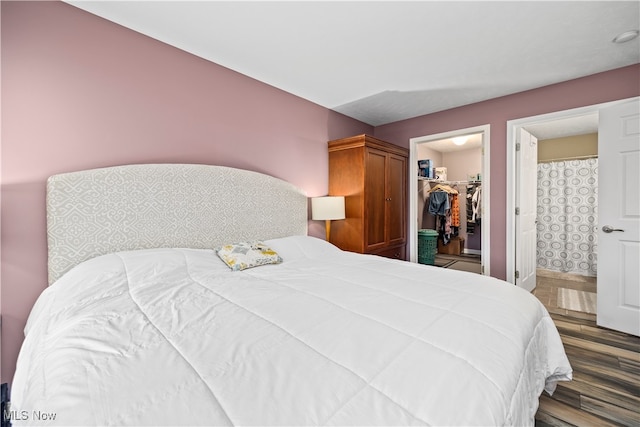 bedroom with a spacious closet, a closet, and dark hardwood / wood-style flooring