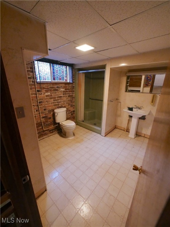 bathroom with sink, brick wall, a paneled ceiling, walk in shower, and toilet