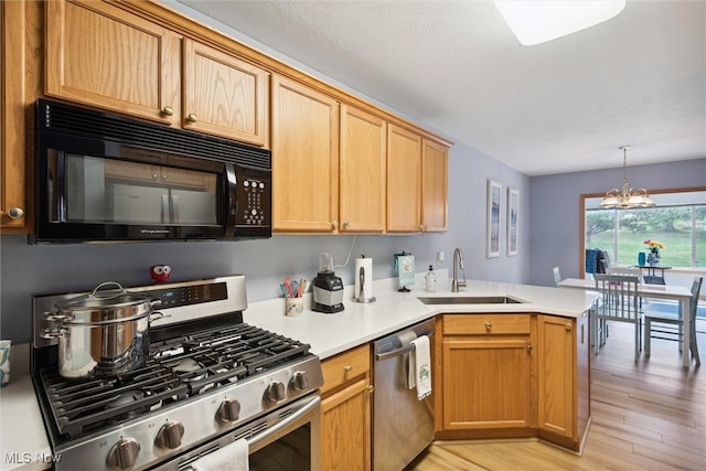 kitchen with sink, kitchen peninsula, a chandelier, stainless steel appliances, and light hardwood / wood-style floors