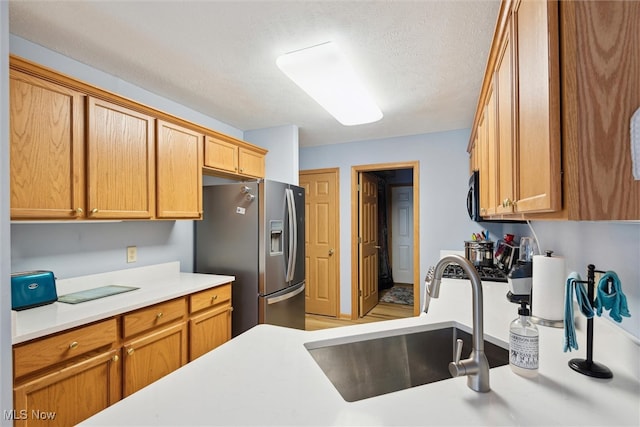 kitchen with a textured ceiling, sink, and stainless steel fridge