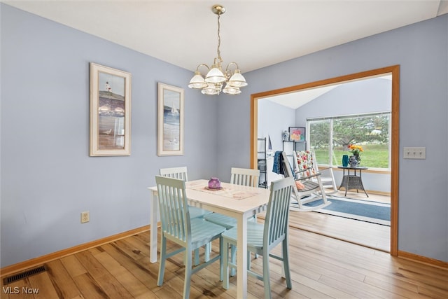 dining space featuring a notable chandelier, lofted ceiling, and hardwood / wood-style floors