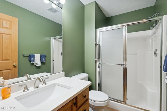 bathroom featuring walk in shower, vanity, toilet, and a textured ceiling