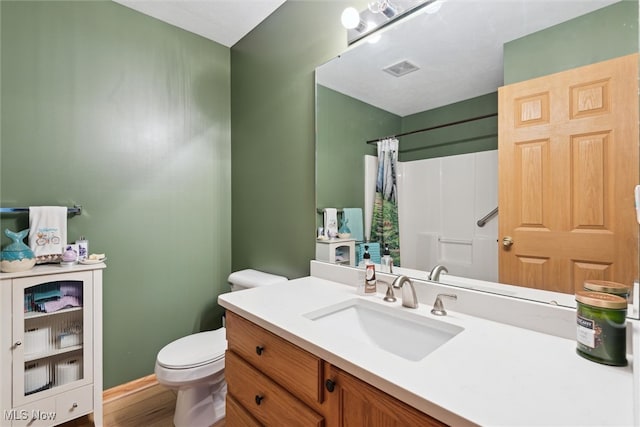 bathroom with walk in shower, vanity, hardwood / wood-style floors, and toilet