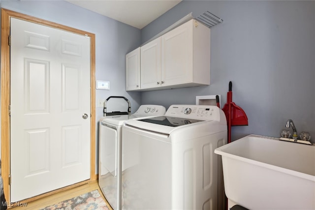 laundry room featuring cabinets, light hardwood / wood-style floors, washing machine and dryer, and sink